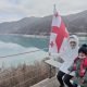 Saudi Arabian kids sitting in front of Georgia flag in Kazbegi.