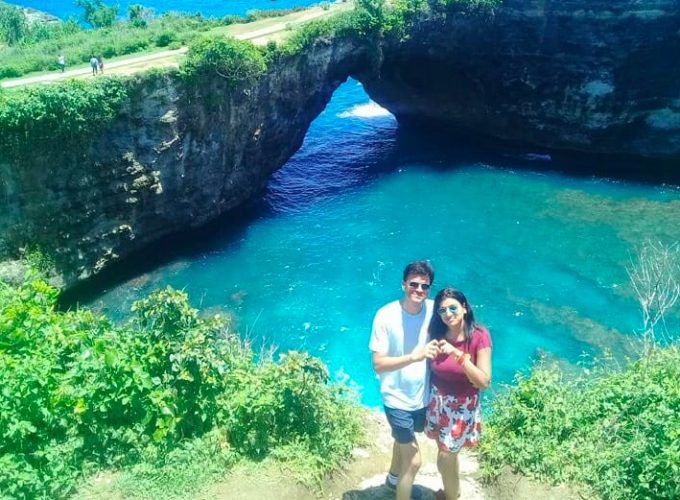 A couple stands on a cliff overlooking the ocean at Broken Beach in Nusa Penida, Bali.