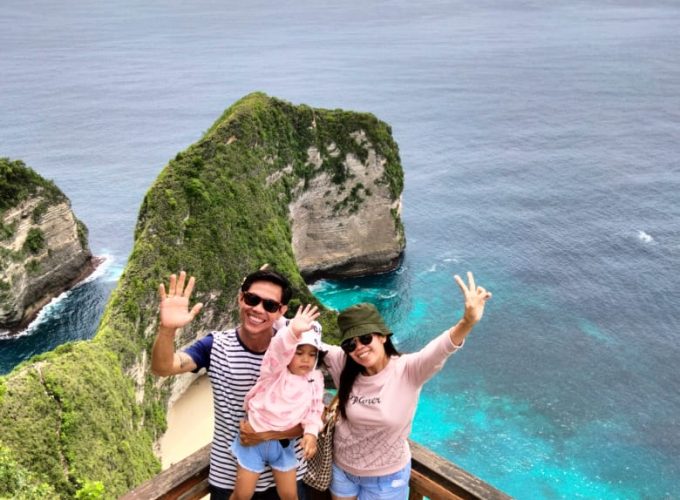 Oka, Novi and their child Indira posing in front of Nusa Penida cliff during the 11 nights 12 days Bali tour package with Nusa Penida.