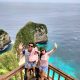 Oka, Novi and their child Indira posing in front of Nusa Penida cliff during the 11 nights 12 days Bali tour package with Nusa Penida.