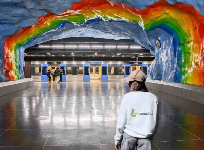 A guest wearing a Lestacworld T-shirt stands confidently on a Stockholm railway station platform, embodying the spirit of the 6 nights 7 days Iceland, Norway, and Sweden tour package.