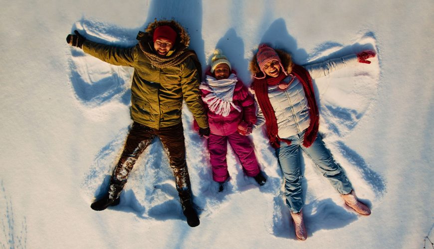 Stepney, Mick, and their son enjoying their Finland tour from Australia, lying on the snow and getting clicked from above.