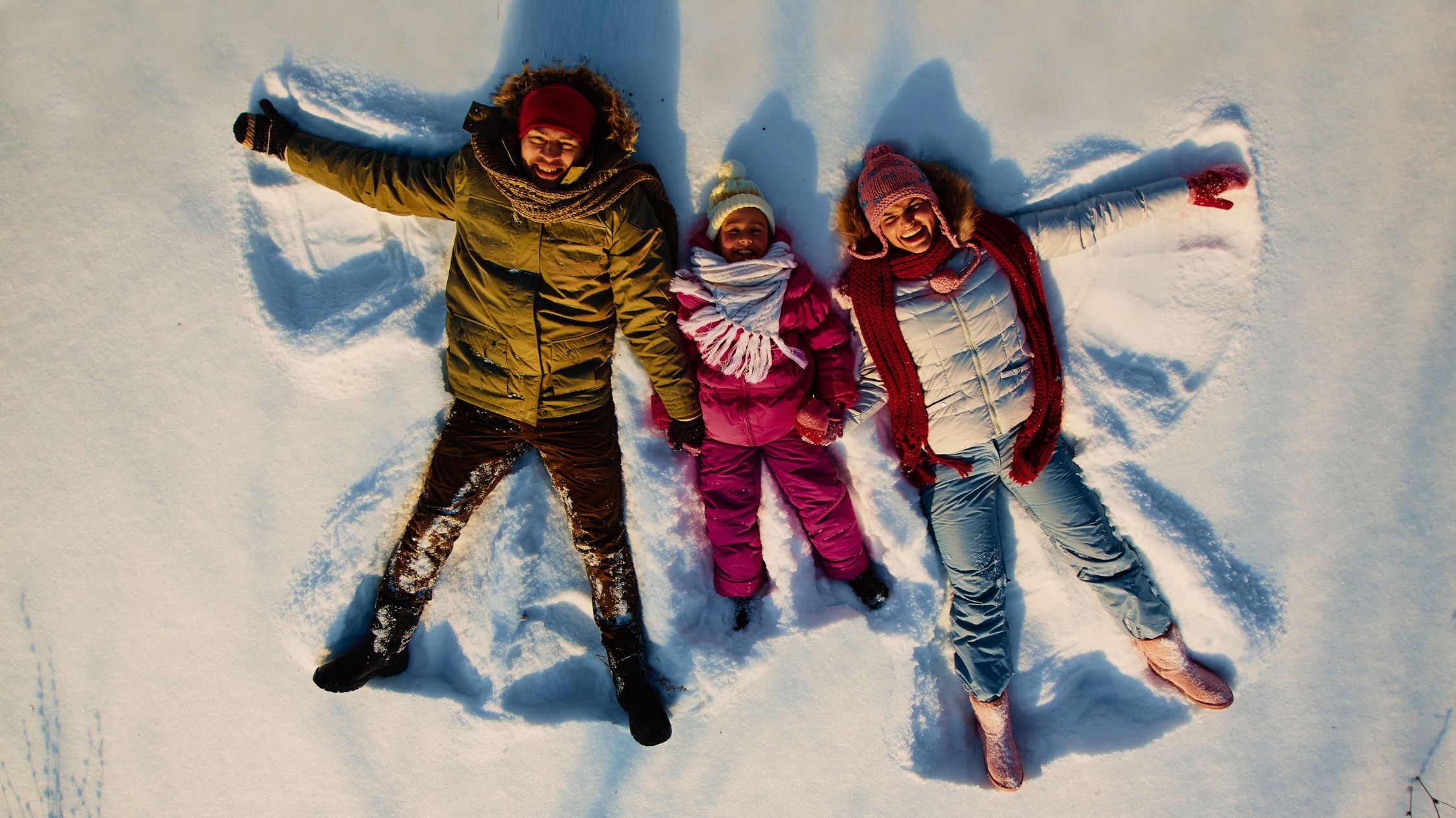 Stepney, Mick, and their son enjoying their Finland tour from Australia, lying on the snow and getting clicked from above.