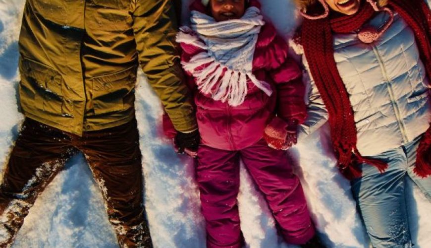 Stepney, Mick, and their son enjoying their Finland tour from Australia, lying on the snow and getting clicked from above.