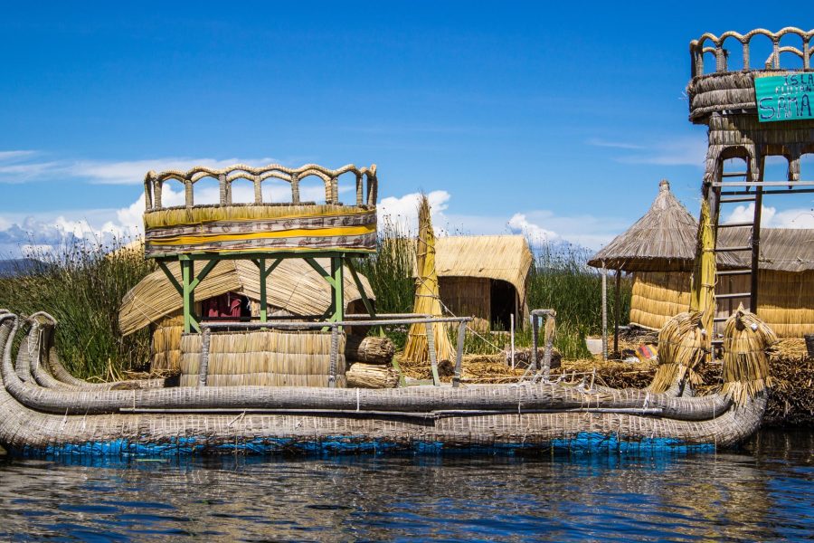 A traditional boat floating on the serene waters of Lake Titicaca, surrounded by the stunning high-altitude landscape, as part of the 10 nights 11 days Peru tour package.