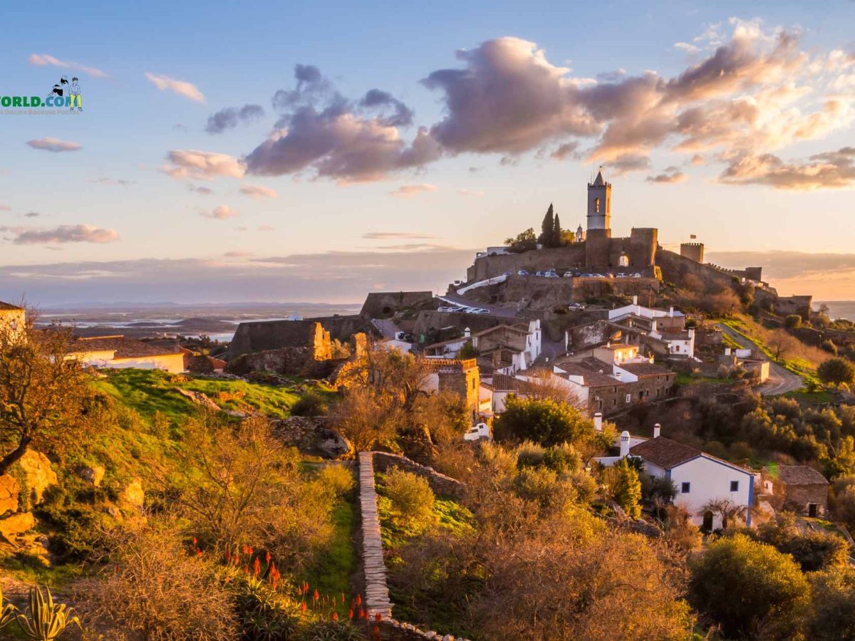 Scenic landscape of Alto Alentejo, Portugal, with rolling hills, vineyards, and a historic village under a clear blue sky. Is June the right time to visit Portugal? Discover the beauty of Alentejo in early summer.